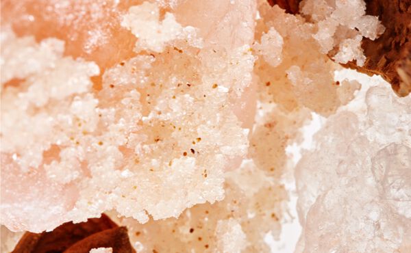 Close-up of pink Himalayan salt crystals and body scrub grains used for exfoliating and glowing skin.